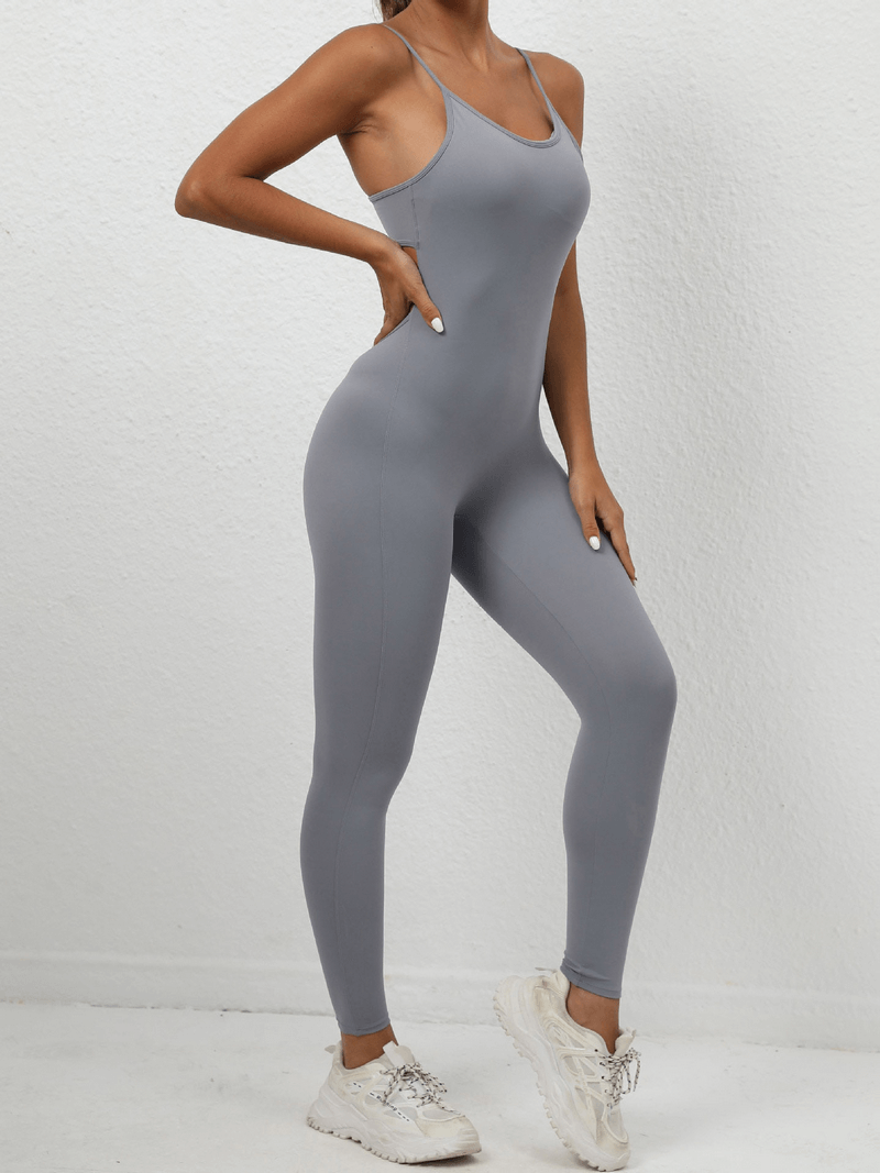 Woman wearing seamless fitness jumpsuit with sexy back and straps, high-waist design, showcasing comfortable fit and style in gray.